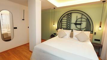 A modern hotel room with a large bed, a round mirror, and a unique geometric headboard.