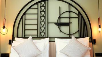 A hotel room with a large bed, two bedside lamps, and a decorative headboard with geometric patterns.