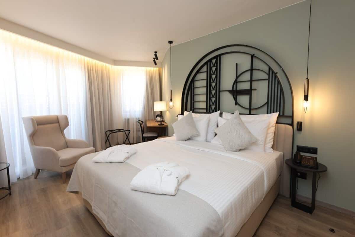 Una habitación de hotel con una cama grande, una silla, un escritorio y una lámpara.