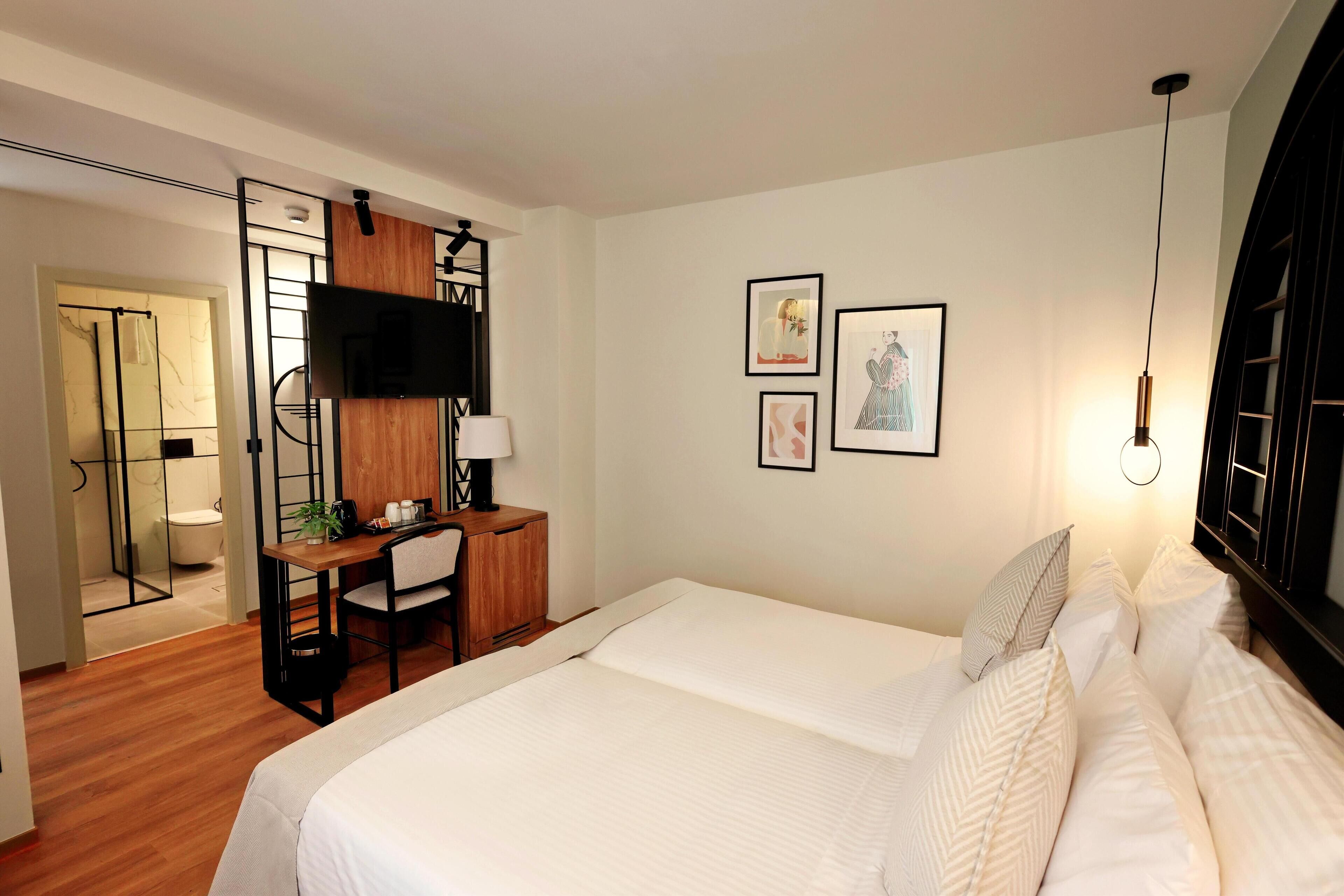 Ein modernes Hotelzimmer mit Bett, Schreibtisch und Duschbereich.