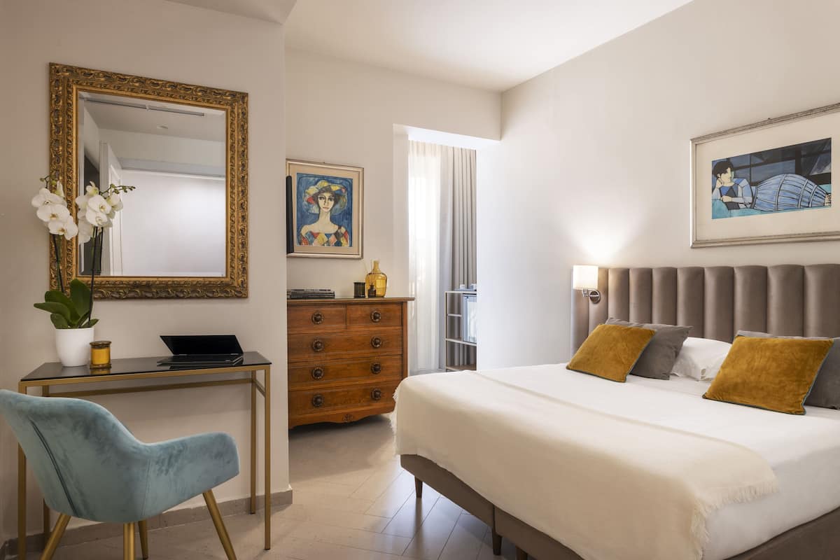 A bedroom with a bed, a desk, a chair, a dresser, and a mirror.