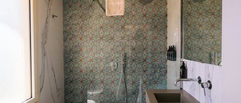 A modern bathroom with a bathtub, a shower with a patterned wall, and a vanity with a large mirror.
