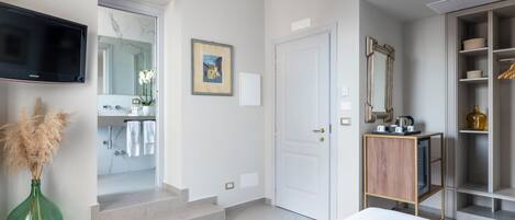 Une chambre d’hôtel avec un lit, une télévision, une salle de bain avec un miroir, un tableau et une armoire.