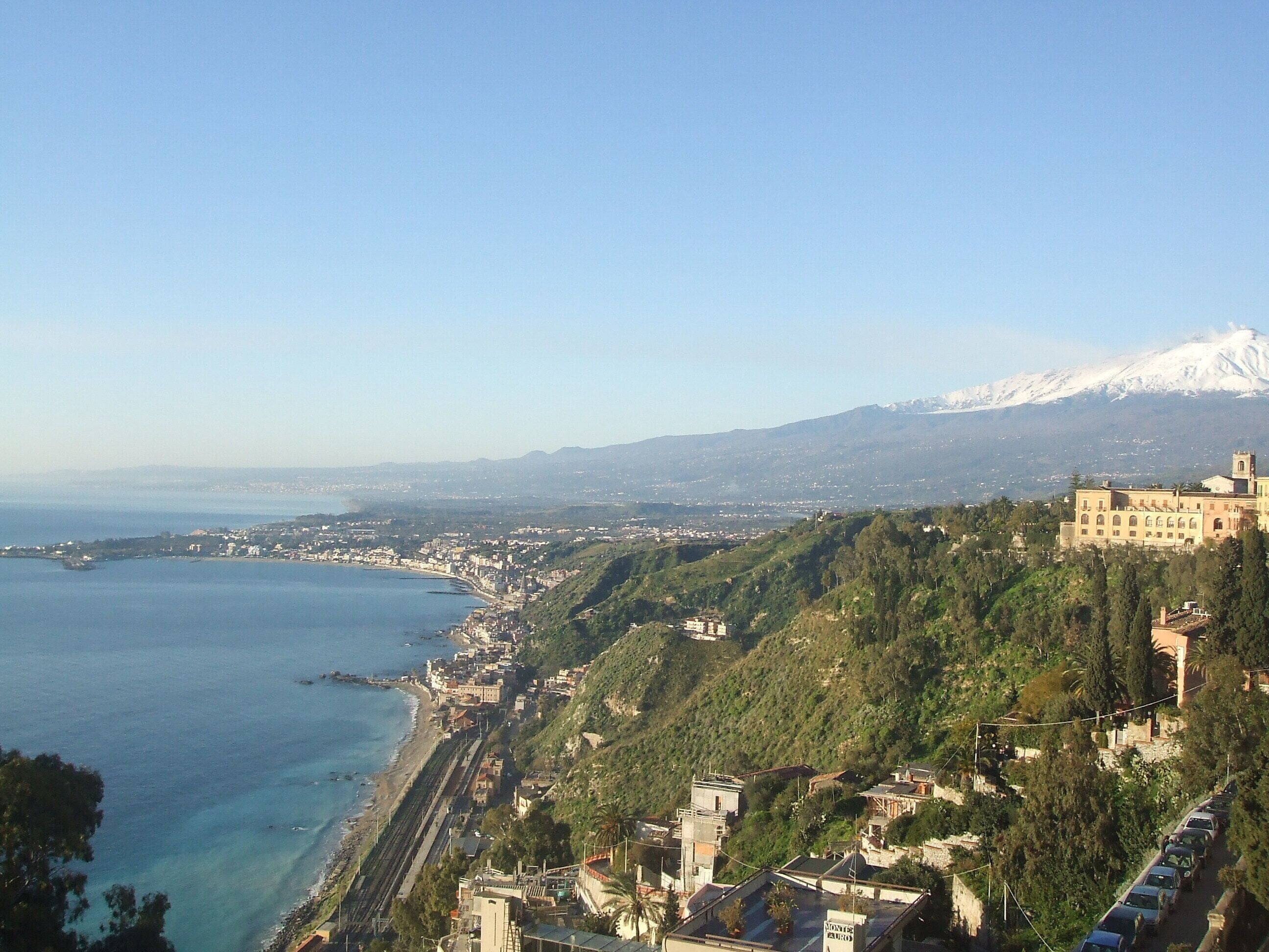 Un paysage urbain côtier avec une colline imposante sur laquelle se trouve un bâtiment historique.