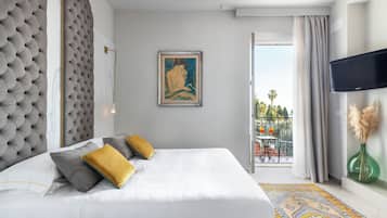 Une chambre d’hôtel avec un grand lit, un tableau au mur, une télévision et un balcon avec vue.