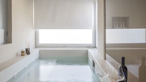 A modern bathroom with a bathtub, a window, and a bottle of wine on the counter. - Hotel Villa Paradiso (Taormina)