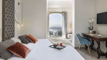 A hotel room with a bed, a dining table, a chair, a TV, and a balcony with a view.