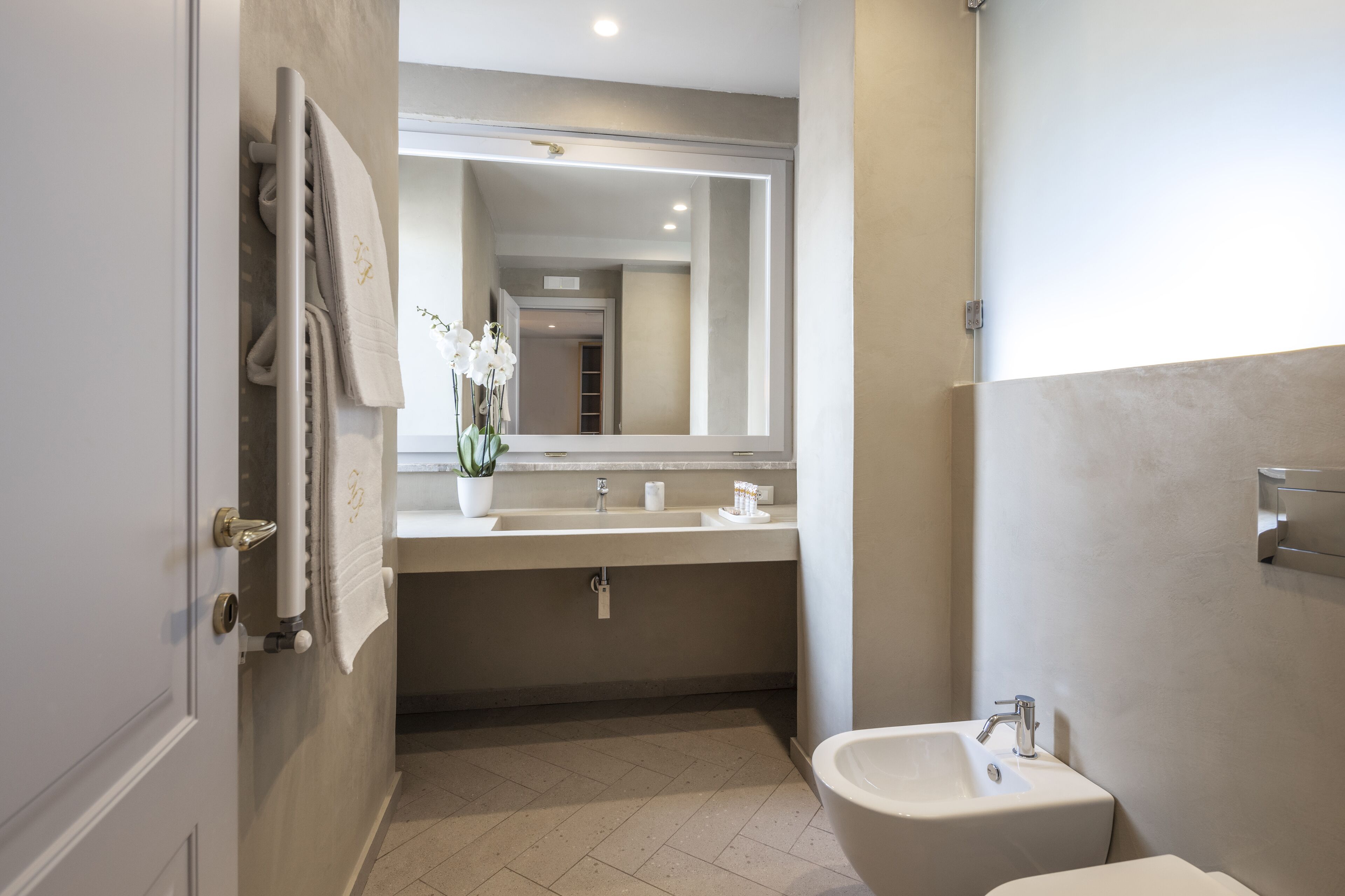 Un baño moderno con lavamanos doble, un espejo grande, inodoro y toallero.