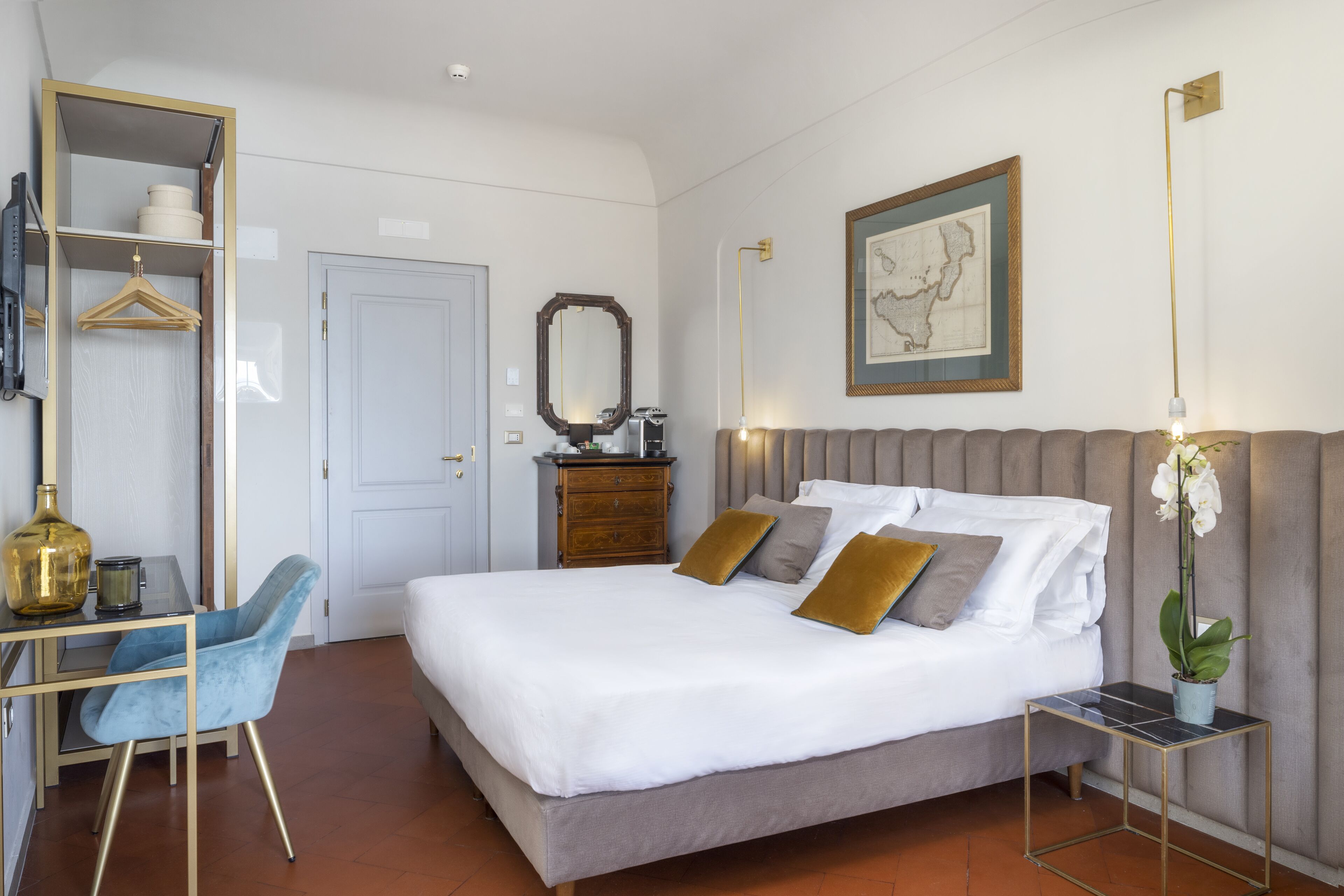Un dormitorio ordenado con cama, mesita de noche, lámpara y un escritorio con silla.