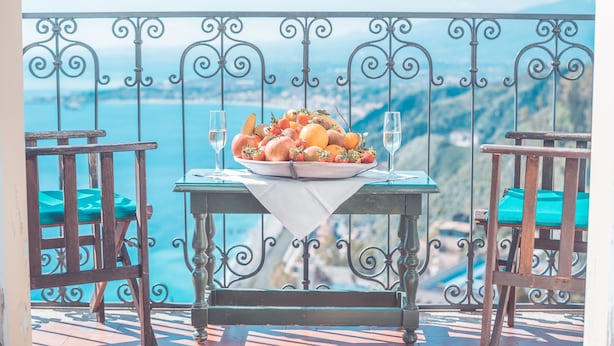 A balcony with a table set for a meal, overlooking a scenic view. - Hotel Villa Paradiso (Taormina)