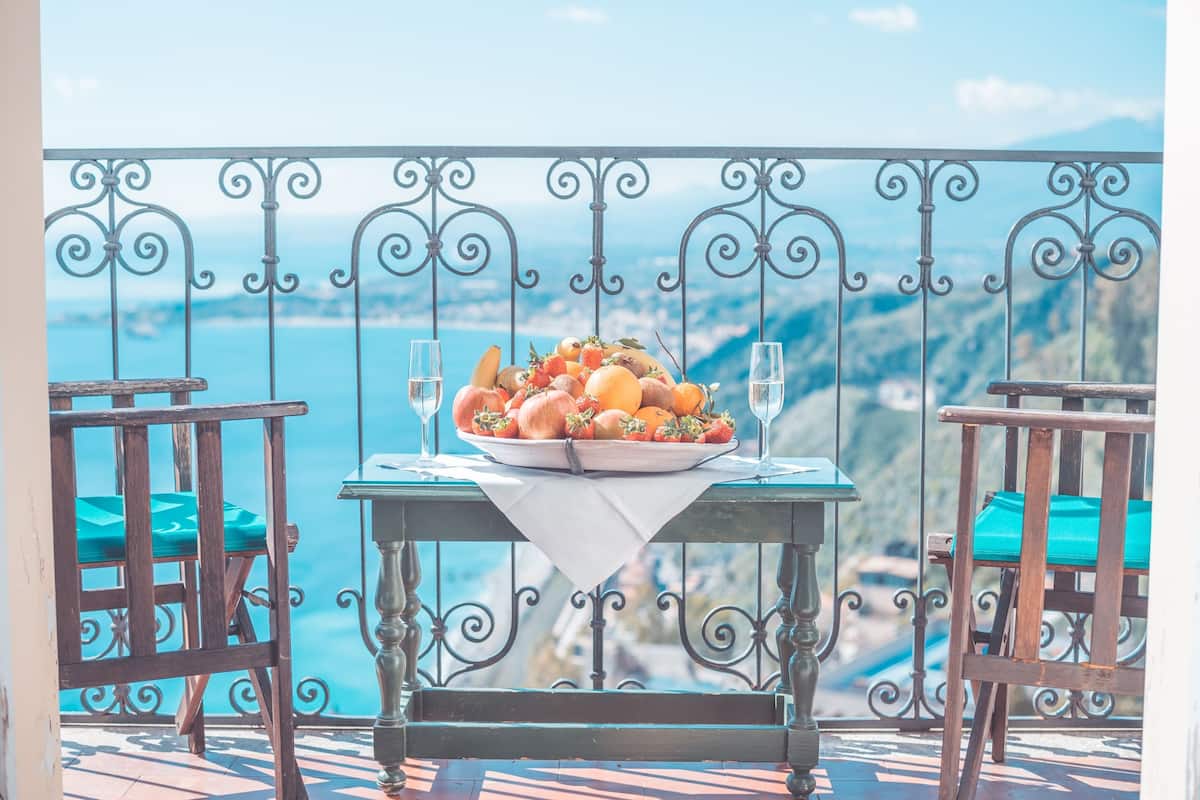 A balcony with a table set for a meal, overlooking a scenic view.