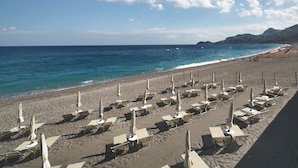 A beach with rows of sun loungers and umbrellas, a sandy shore, and the sea in the background. - Hotel Villa Paradiso (Taormina)