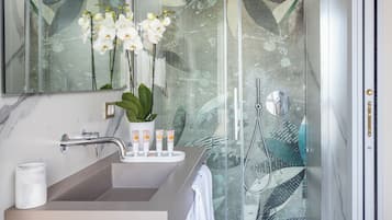 A modern bathroom with a large mirror, a sink, and a shower.