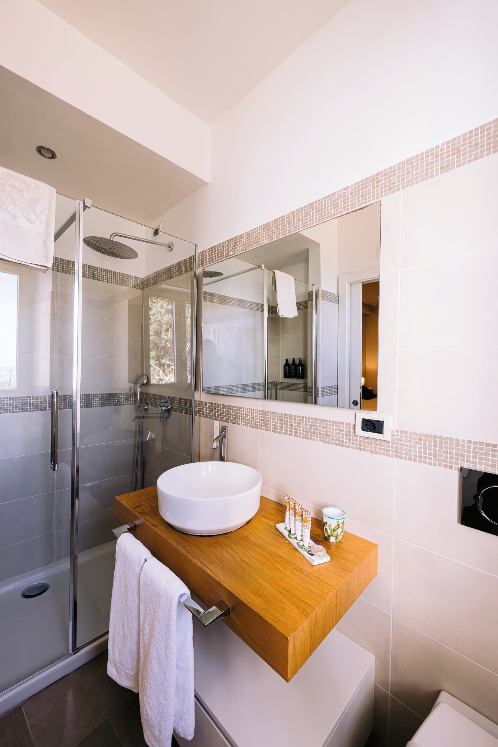 A modern bathroom with a glass-enclosed shower, a wooden vanity, and a large mirror.