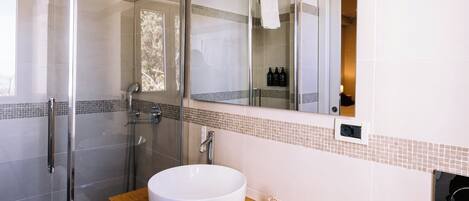 A modern bathroom with a glass-enclosed shower, a wooden vanity, and a large mirror.