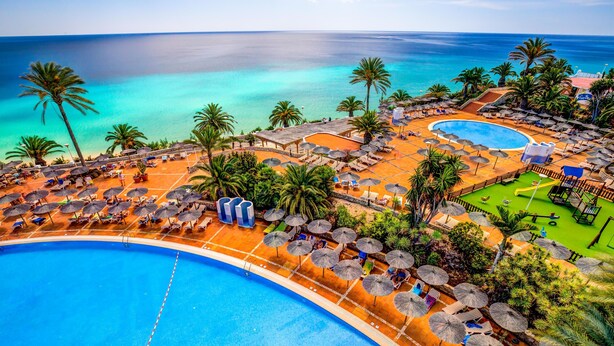 A resort with a large pool, sun loungers, umbrellas, and palm trees. - SBH Club Paraíso Playa - All Inclusive (Pajara)