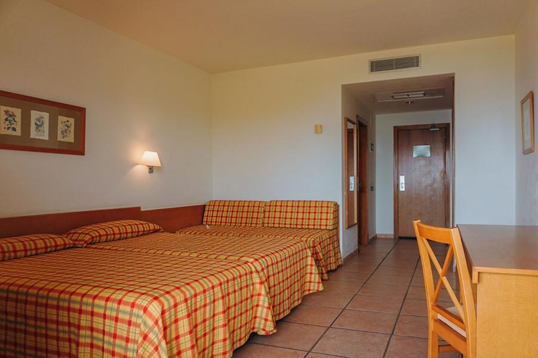 Habitació d'hotel amb dos llits, una taula i una cadira.