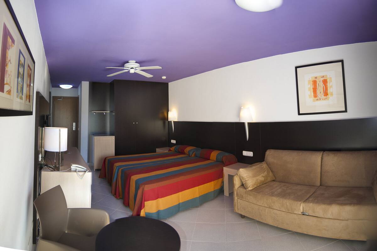 A hotel room with a bed, a sofa, a desk, and a chair.