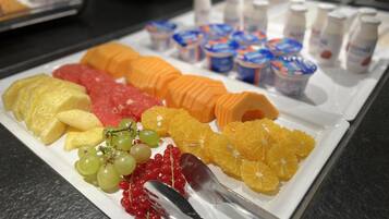 A fruit platter with various fruits and a spoon on a white plate.