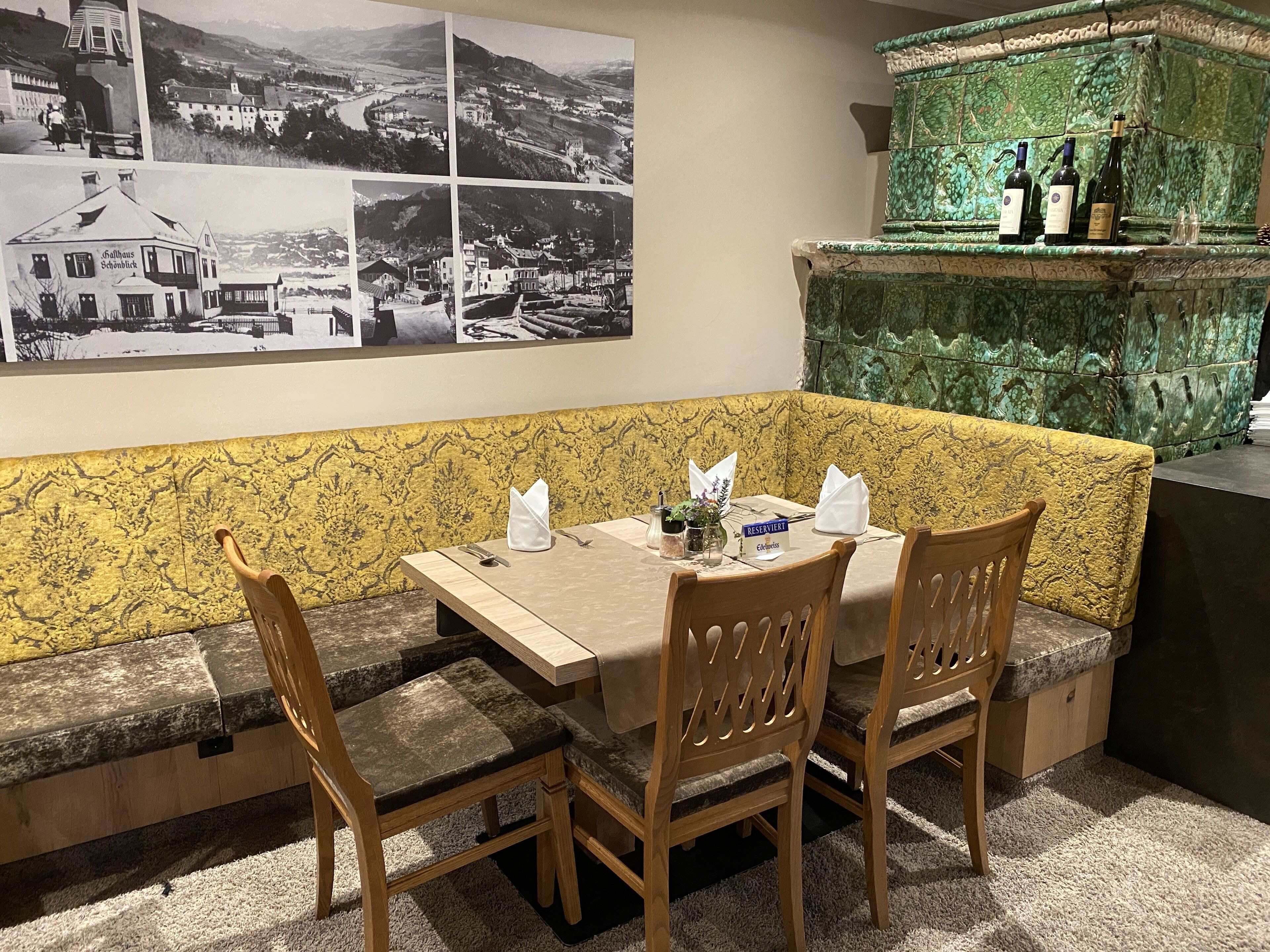 Un restaurante con un banco de mármol, una mesa para dos personas y una pared con fotografías en blanco y negro.