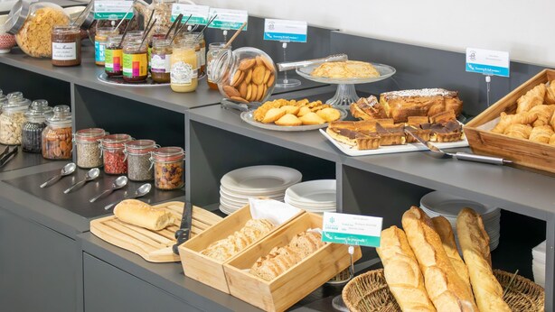 Un bufé con diversas opciones de comida, incluyendo pastelería, pan y salsas.