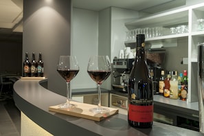 A bar area with two wine glasses and a bottle of wine on a counter.