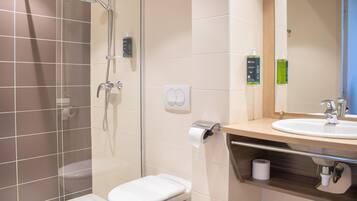 A modern bathroom with a glass-enclosed shower, a toilet, a sink, and a mirror.