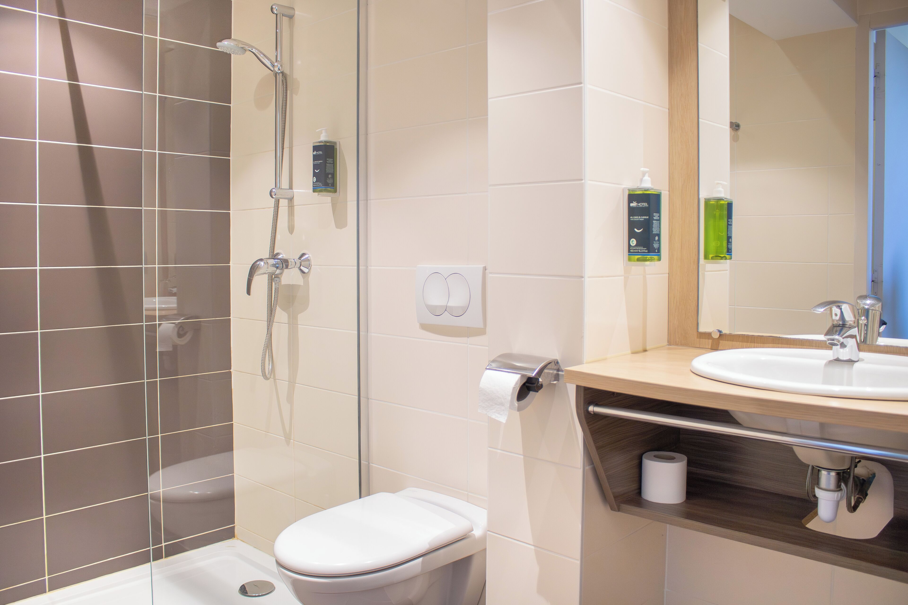 Un baño moderno con ducha de vidrio, inodoro y lavamanos con espejo.