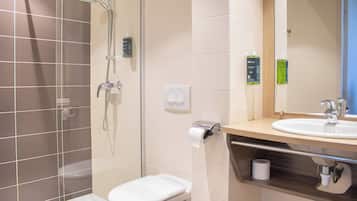 Un baño moderno con ducha de vidrio, inodoro y lavamanos con espejo.
