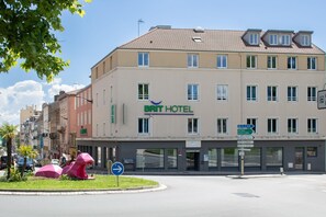 Un hôtel avec une enseigne indiquant « BRIT HOTEL » et des panneaux de signalisation indiquant les lieux d’intérêt à proximité.