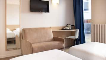A hotel room with two beds, a sofa, a desk with a chair, a flat-screen TV, and a window with curtains.