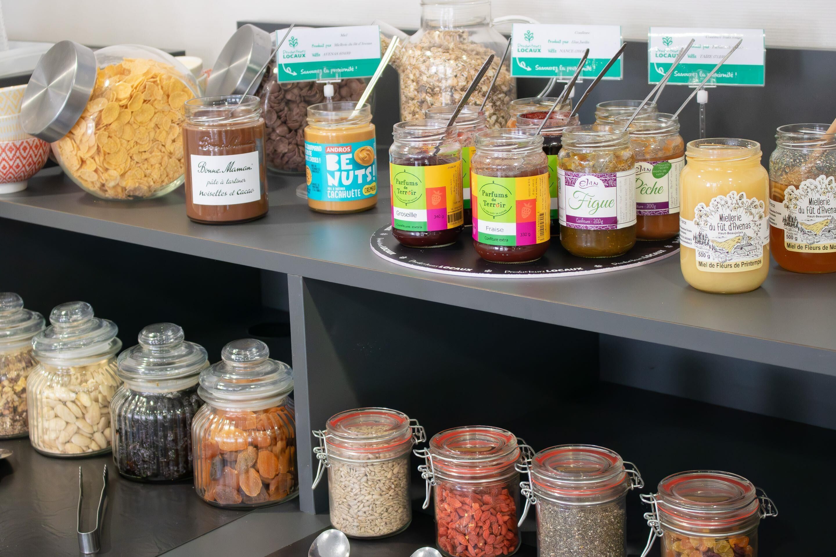 Diversos alimentos em potes dispostos sobre uma mesa, incluindo nozes, sementes e frutas secas.