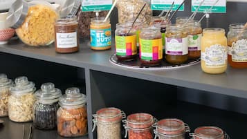 Diversos alimentos em potes dispostos sobre uma mesa, incluindo nozes, sementes e frutas secas.