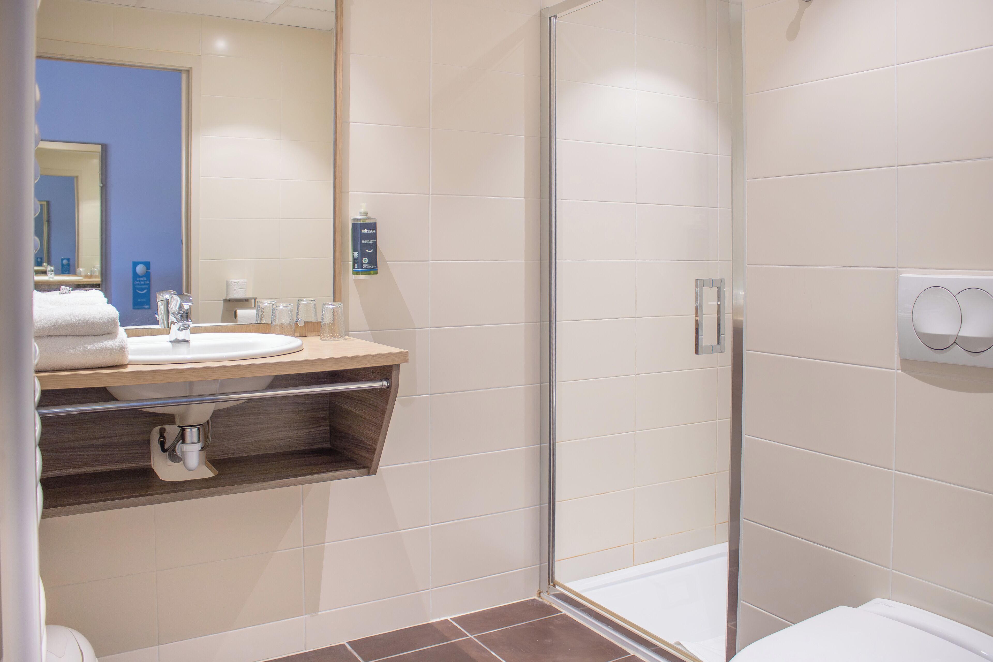 Un baño moderno con cabina de ducha de vidrio, un lavabo con espejo y un perchero para toallas.