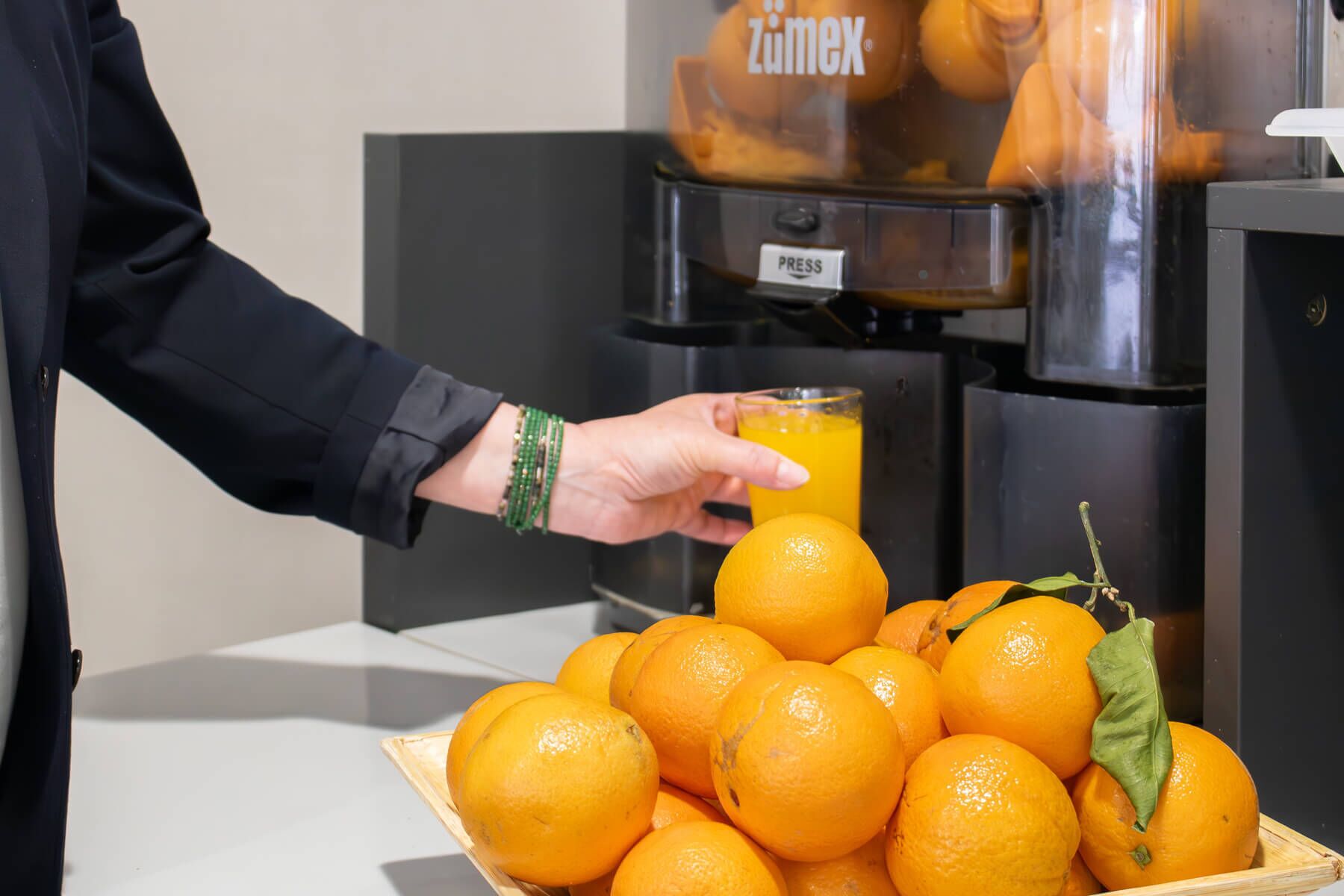 Una persona vertiendo jugo de naranja desde un dispensador en un vaso.
