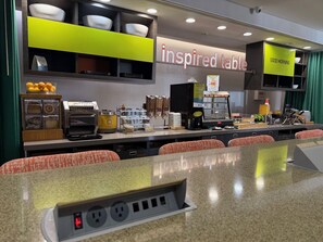 A breakfast area with a counter, seating, and a sign that reads 'inspired table'.