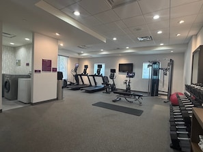 A gym with treadmills, a stationary bike, a rowing machine, and free weights.