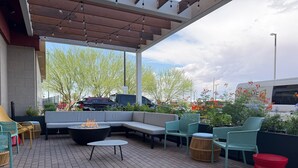 Un patio al aire libre con asientos, una chimenea y vista a un estacionamiento.