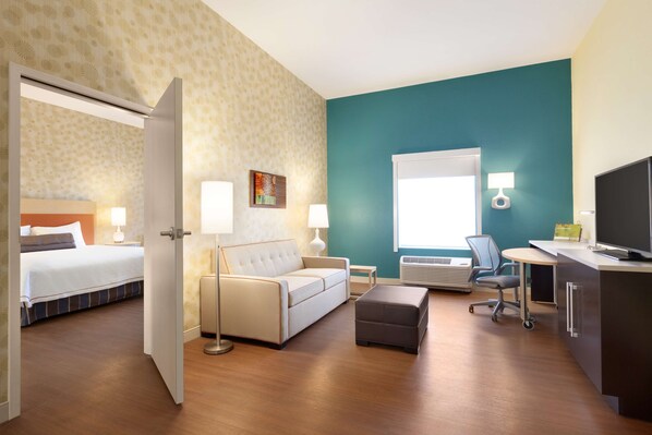 Een hotelkamer met een bed, een slaapbank, een bureau, een stoel en een televisie.