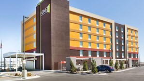 Un hotel de varios pisos con un llamativo letrero que dice 'HOME', un estacionamiento techado y un cielo despejado.