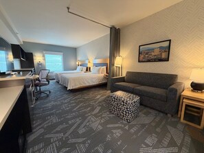 Een hotelkamer met een bed, een bureau, een slaapbank en een kamer met een patroon.