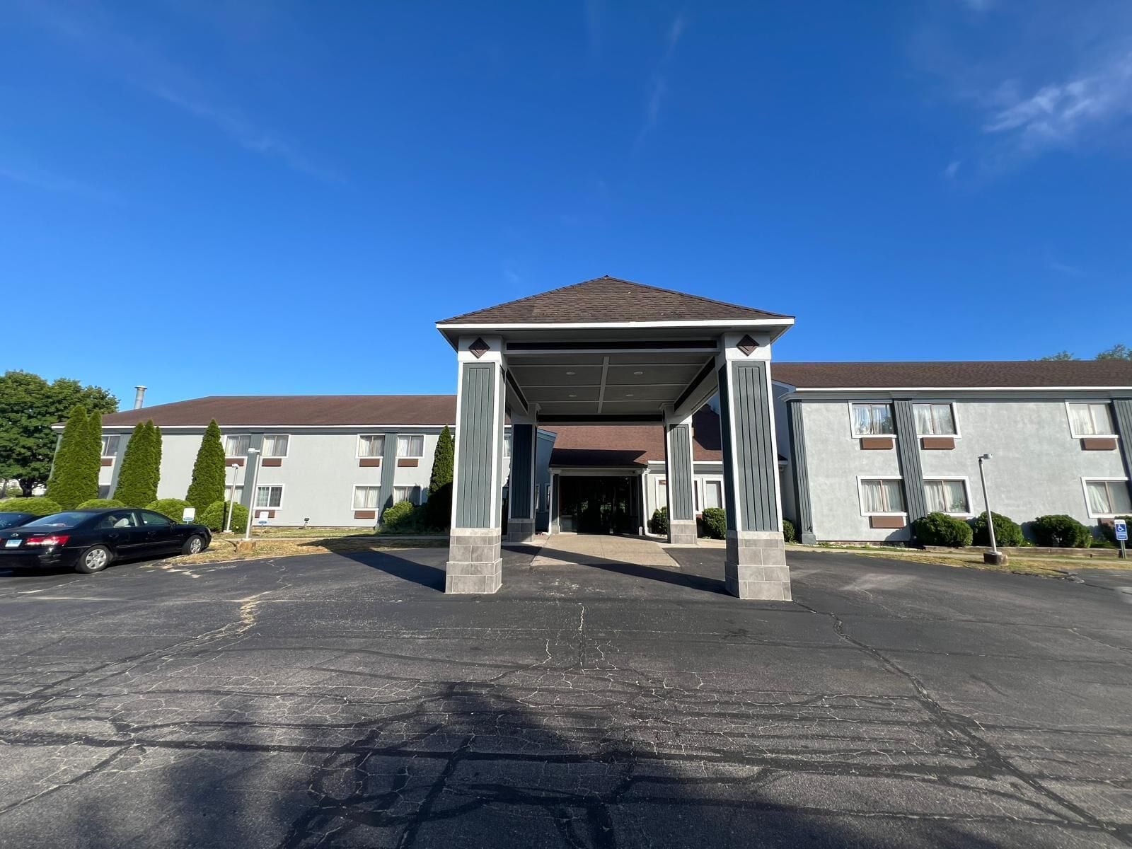 A building with a covered entrance, a parking lot, and a clear blue sky.