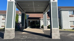 Una entrada cubierta con una puerta central, flanqueada por dos columnas, que conduce a un edificio con techo marrón.