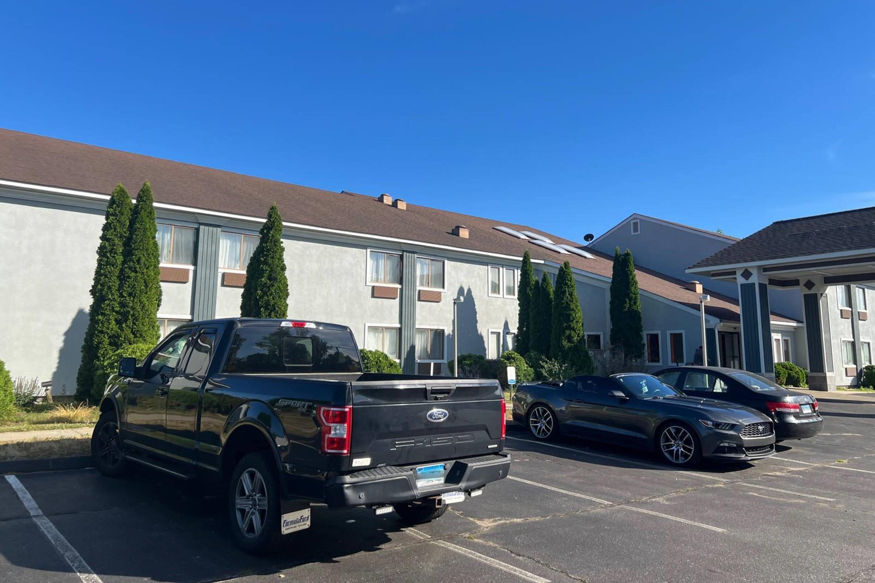A parking lot with a black pickup truck and two cars.