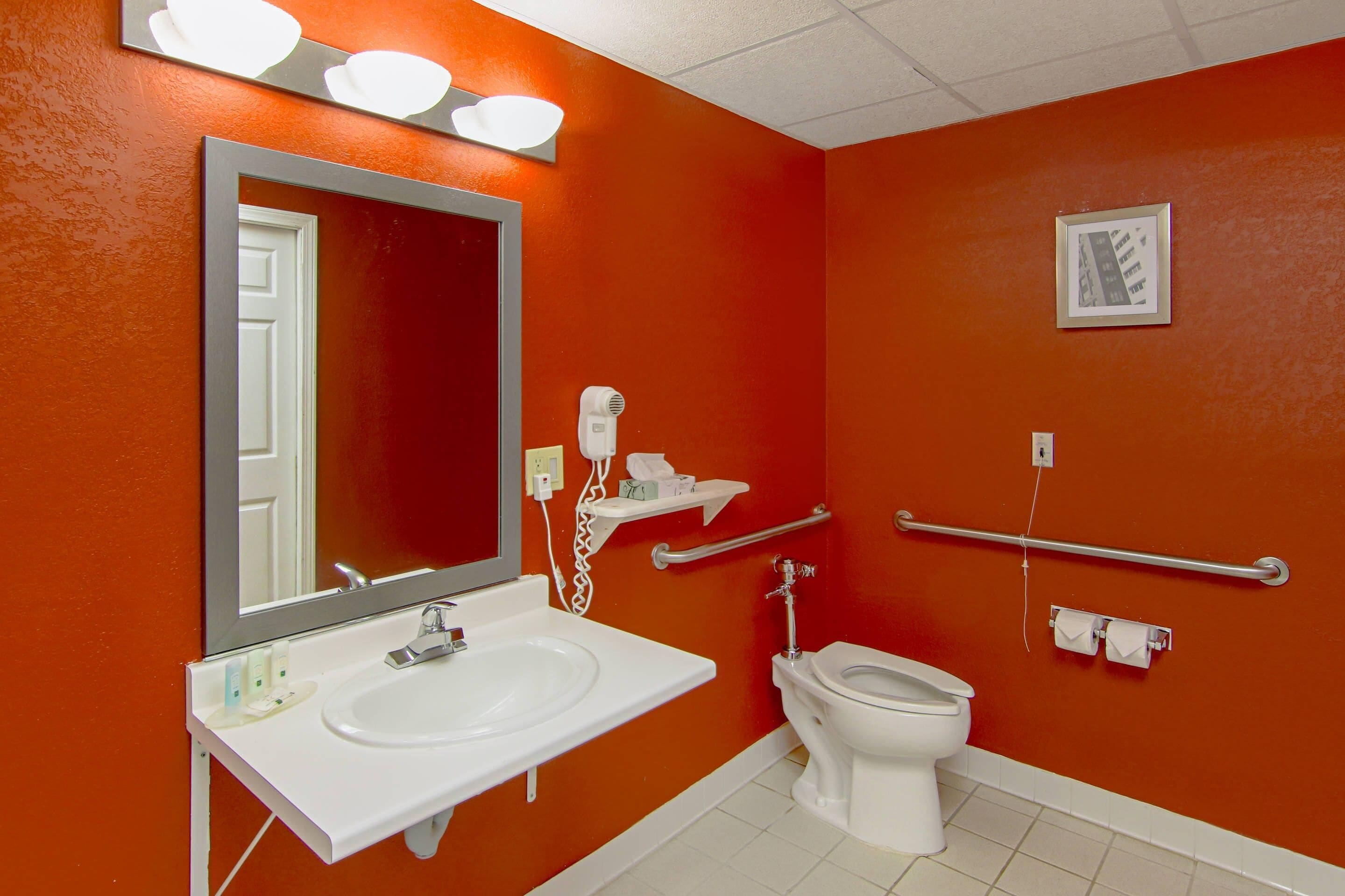 A bathroom with a white sink, a toilet, a hand dryer, and a mirror.
