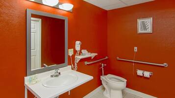 A bathroom with a white sink, a toilet, a hand dryer, and a mirror.