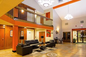 A hotel lobby with a high ceiling, a staircase, a reception desk, and a seating area with sofas and a coffee table. - Quality Inn Plainfield I-395 (Plainfield)