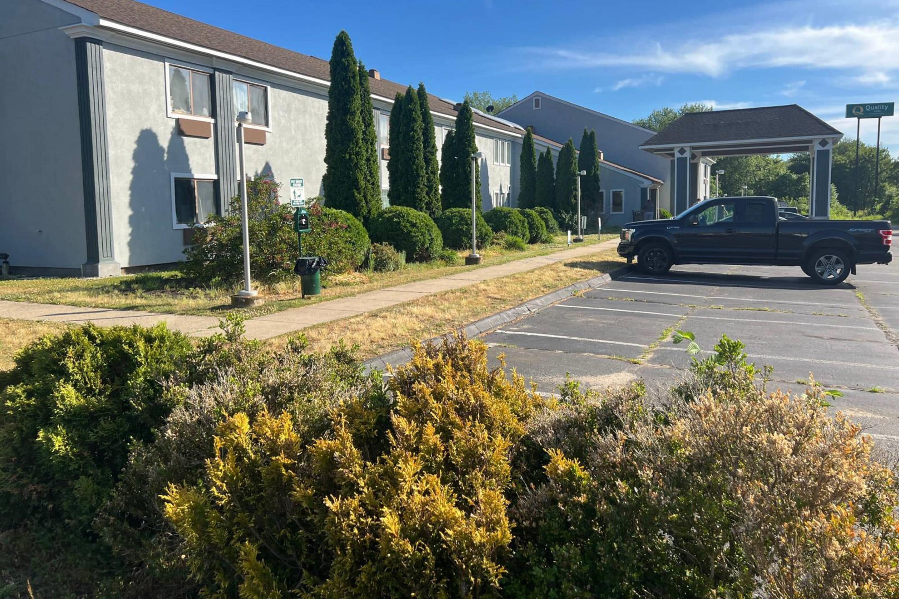 Un bâtiment avec un parking, un camion et un espace abrité.