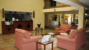 Un vestíbulo con sofás rojos a rayas, un mostrador de recepción, una máquina de café y una zona de comedor con sillas.