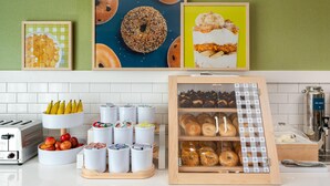 A kitchen counter with a toaster, a bowl of apples, and a display of bagels. - Spark by Hilton Douglasville Atlanta West (Douglasville)